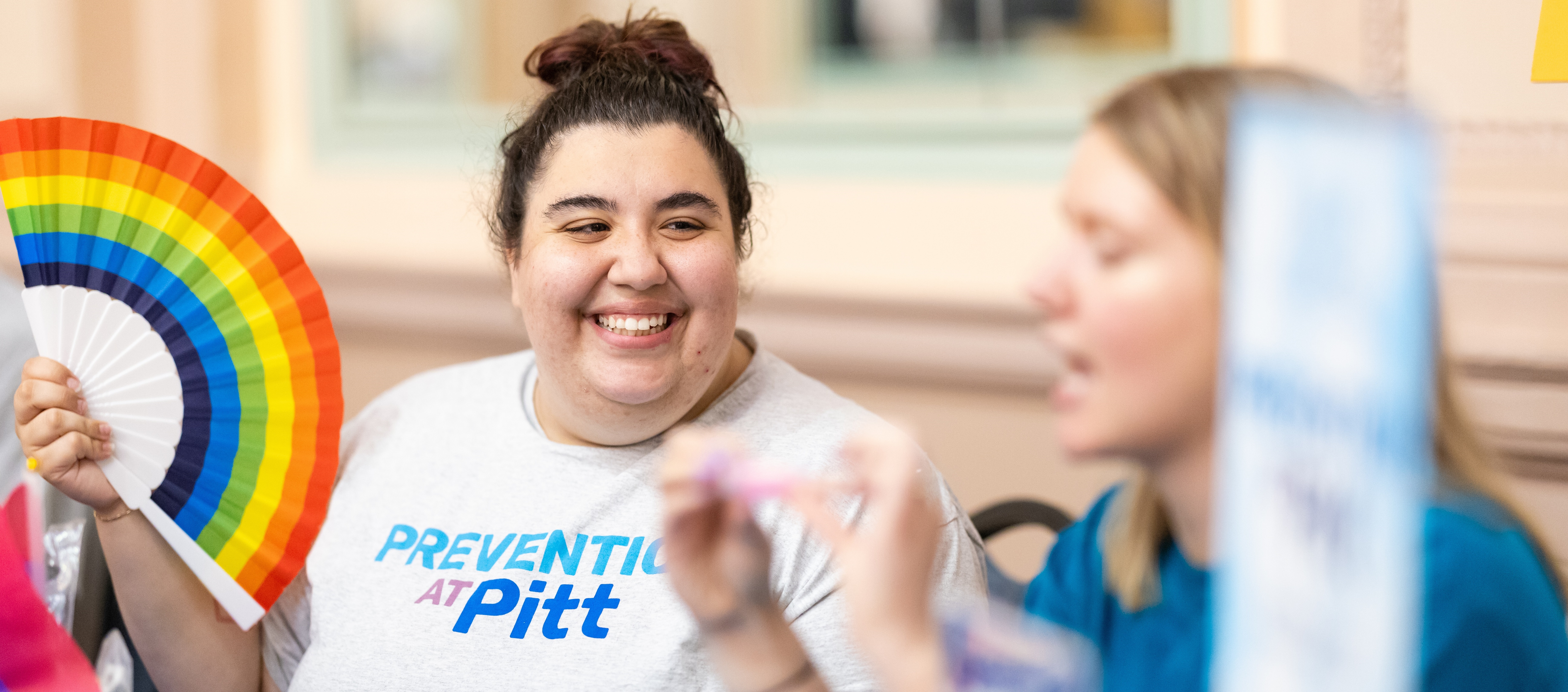 student smiling while waving paper fan